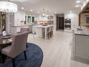 Grey luxury vinyl flooring in a kitchen remodel with white cabinetry and blue area rug