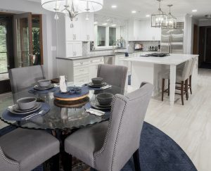 Kitchen remodel with grey upholstered dining set, glass table, luxury vinyl flooring and white cabinetry