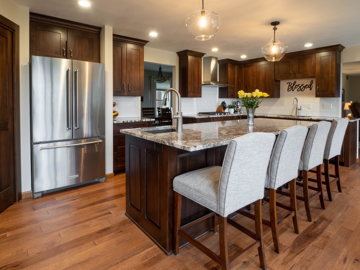 Kitchen remodel featuring wood cabinetry, granite countertops, and grey upholstered bar stools