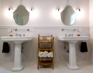 two white pedestal sinks and white tile floor