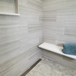 shower remodel with tiled walk-in shower and a granite bench