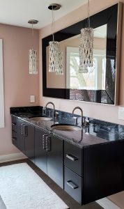 bathroom remodel with black floating vanity and black granite countertops and crystal pendant lights