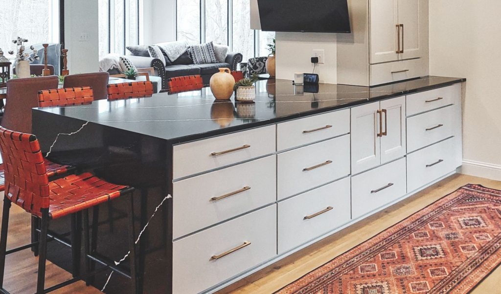 Custom kitchen design with white cabinets, black waterfall granite countertops and boho decor. 