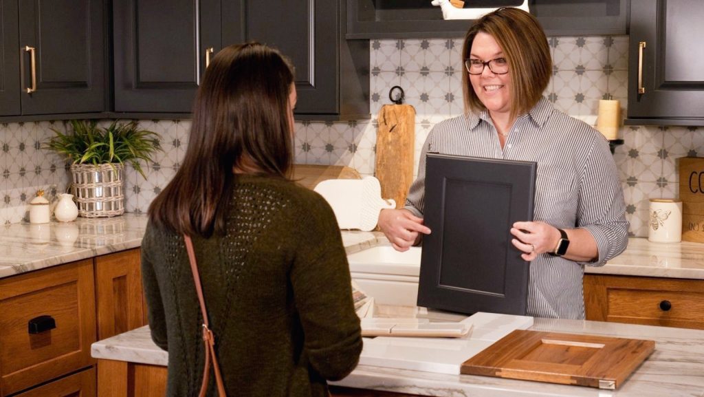 kitchen designer showing cabinets with a customer