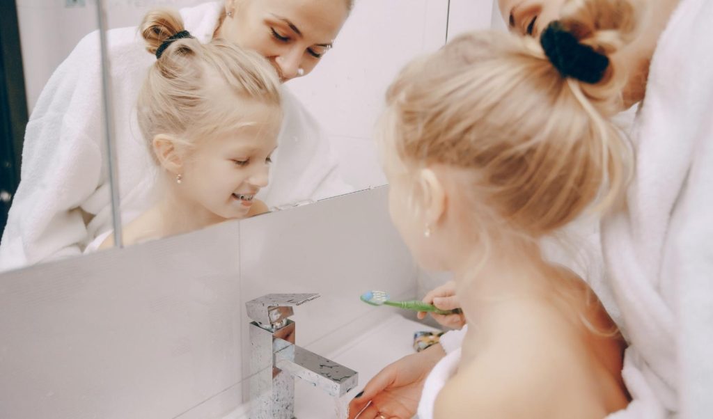 mother and daughter in brushing teeth in bathroom