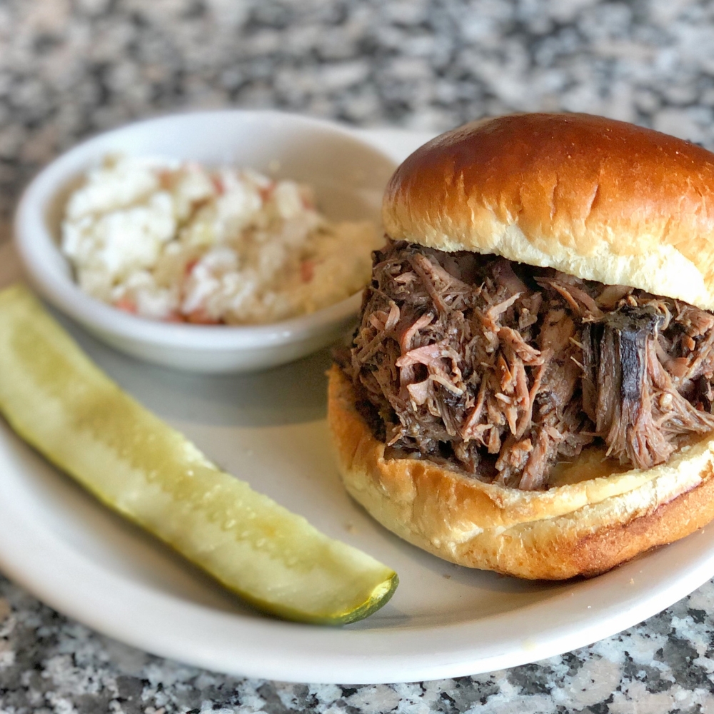 pot roast sandwich with a pickle and a cup of coleslaw at hearthrock cafe in rockford, il