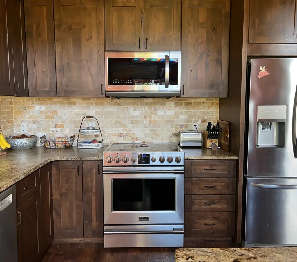 benson stone company rustic kitchen design with wood stained cabinets, stone tile backsplash, leathered granite countertops