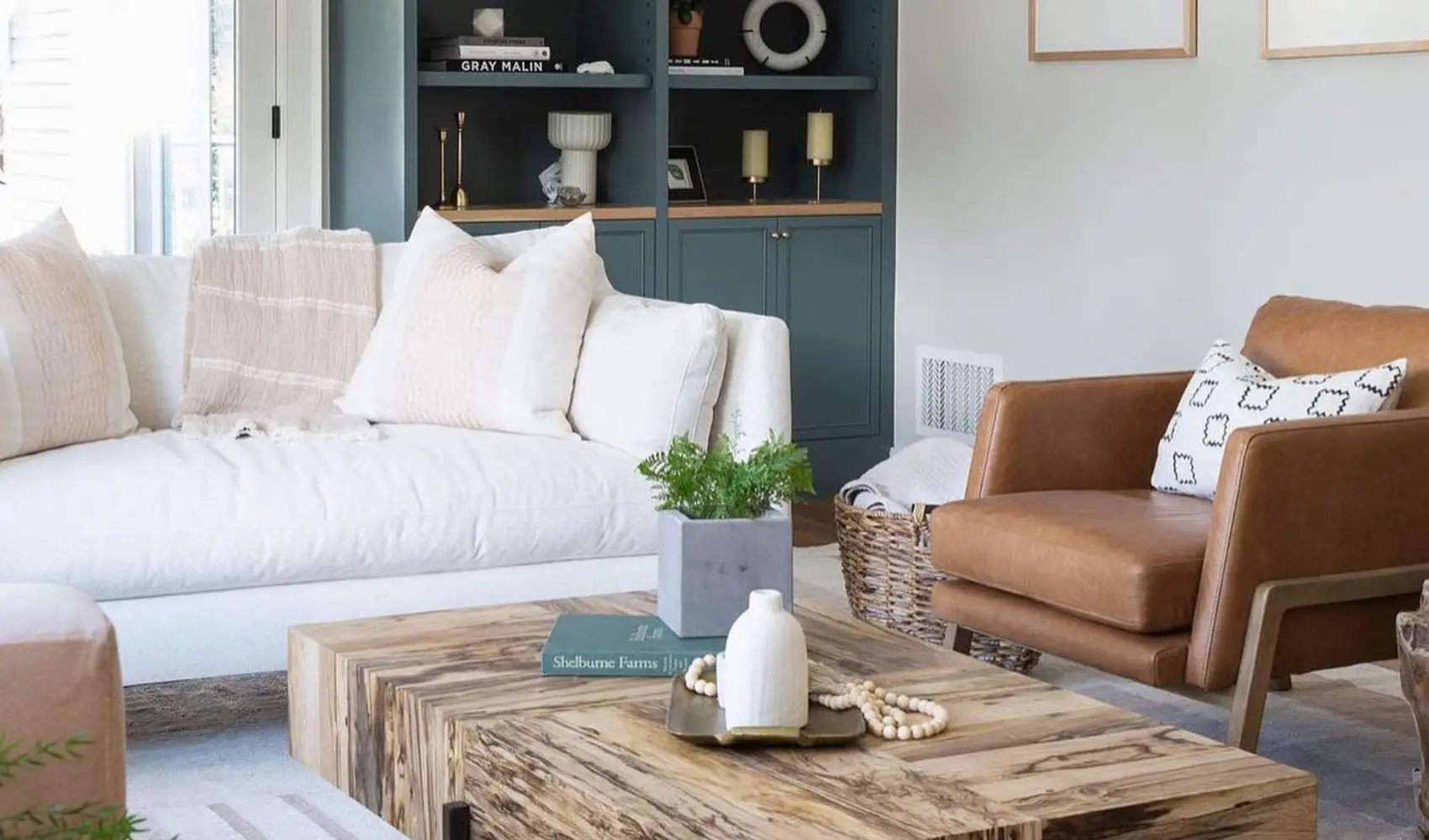 room designed by a furniture designer featuring white Rowe sofa, leather accent chair, green cabinet, and wood top coffee table