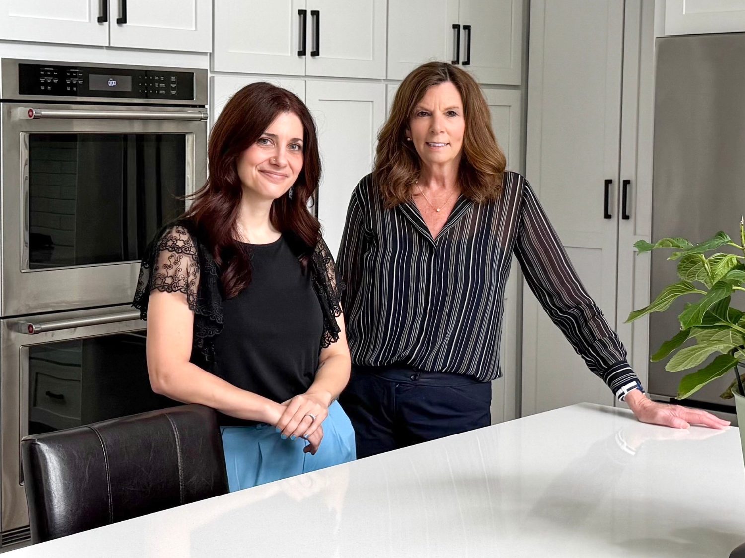 Designer Jessica and the homeowner smiling in a remodeled kitchen.