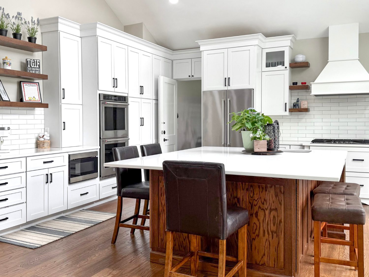 A bright modern transitional kitchen featuring vaulted ceilings, Birch White shaker cabinets, a contrasting dark wood Maple Dusk island with a white quartz top